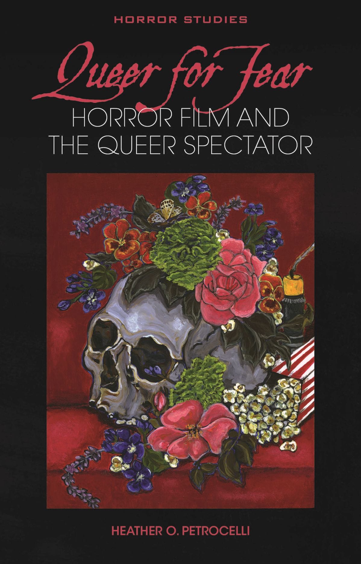 Book cover for Queer for Fear: Horror Film and the Queer Spectator by Heather O. Petrocelli, published in the Horror Studies series. The cover features a still life painting in the tradition of Memento Mori against a dark background. The central image shows a gray human skull and a snuffed-out candle on a classic red velvet movie theatre seat decorated with vibrant flowers including violets, green carnations, pink roses, and pansies. A striped popcorn container with spilling popcorn appears in the corner, combining classic horror imagery with cinema elements. The title appears in two styles: "Queer for Fear" in flowing red script, and "HORROR FILM AND THE QUEER SPECTATOR" in clean white typography below it.